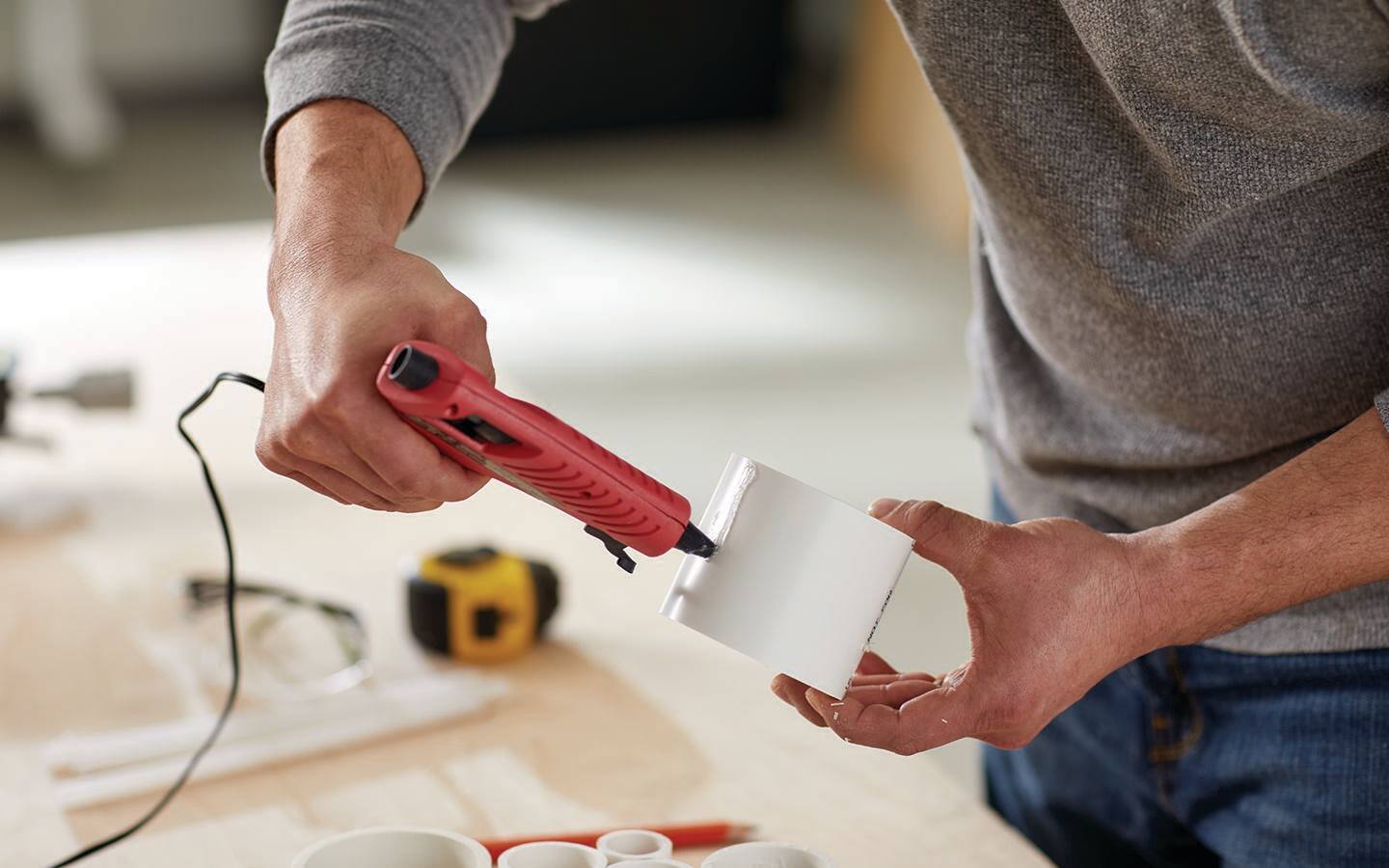 Someone hot gluing a section of PVC pipe. Someone hot gluing a section of PVC pipe.
