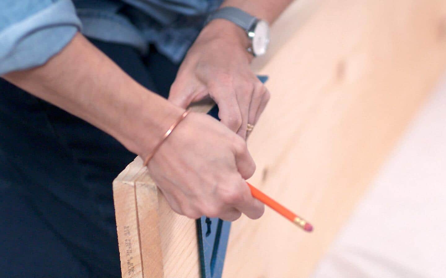 A person using a square to mark measurements on a board. A person using a square to mark measurements on a board.
