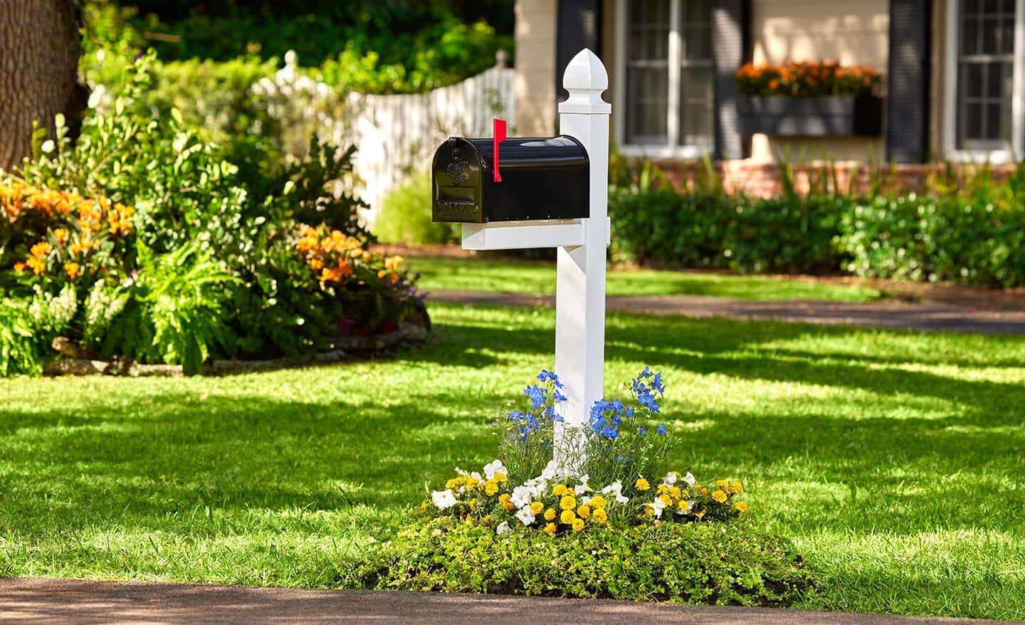 A flower bed surrounds a mailbox in a front yard.