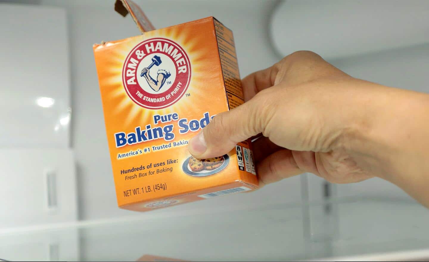 A person holds a box of baking soda.