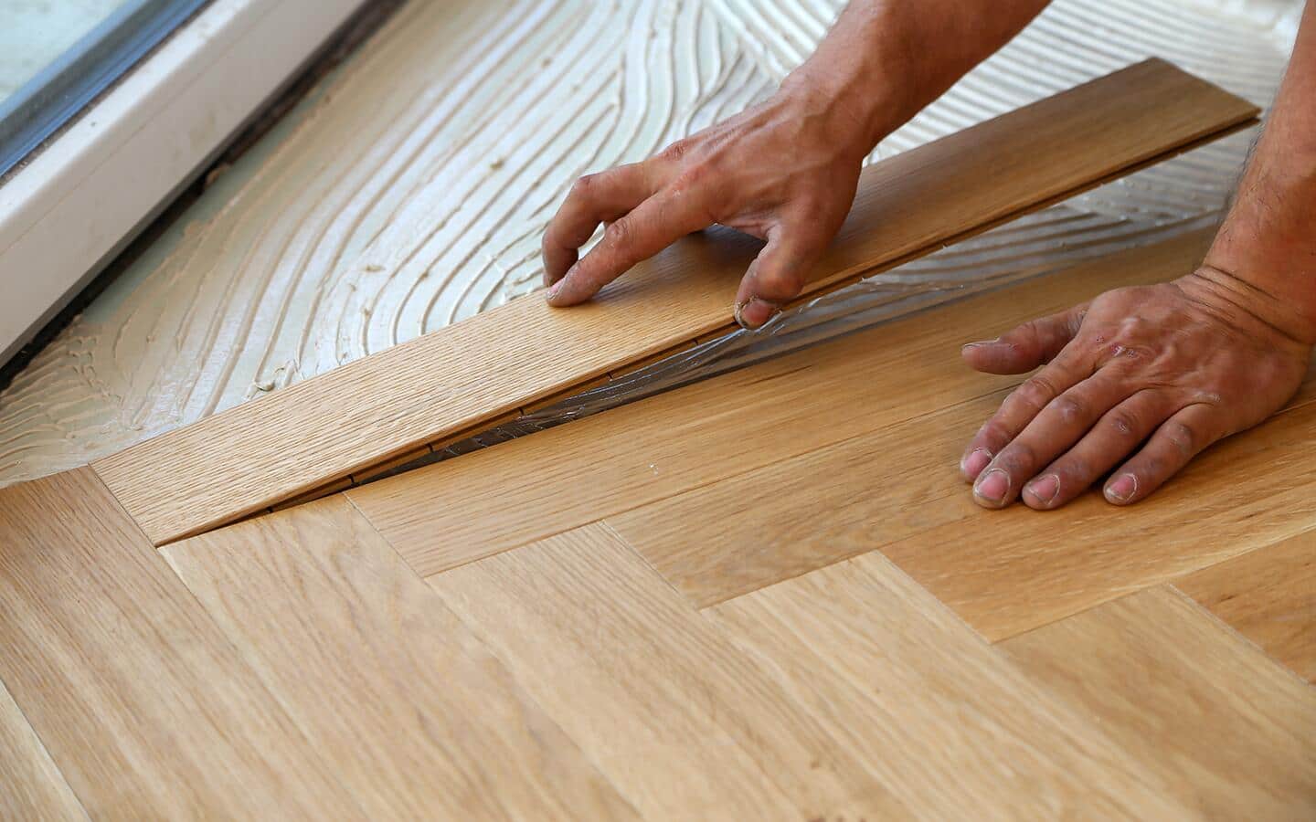 A person lays a parquet tile over a layer of mortar. A person lays a parquet tile over a layer of mortar.