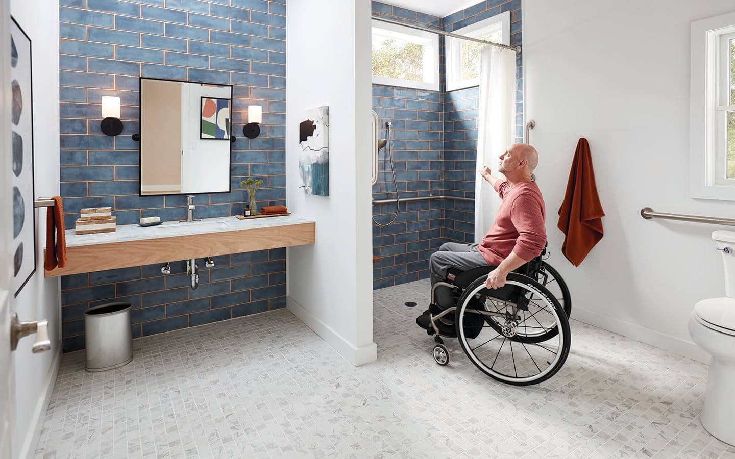 A man in a wheelchair looks at the shower in his accessible bathroom. A man in a wheelchair looks at the shower in his accessible bathroom.