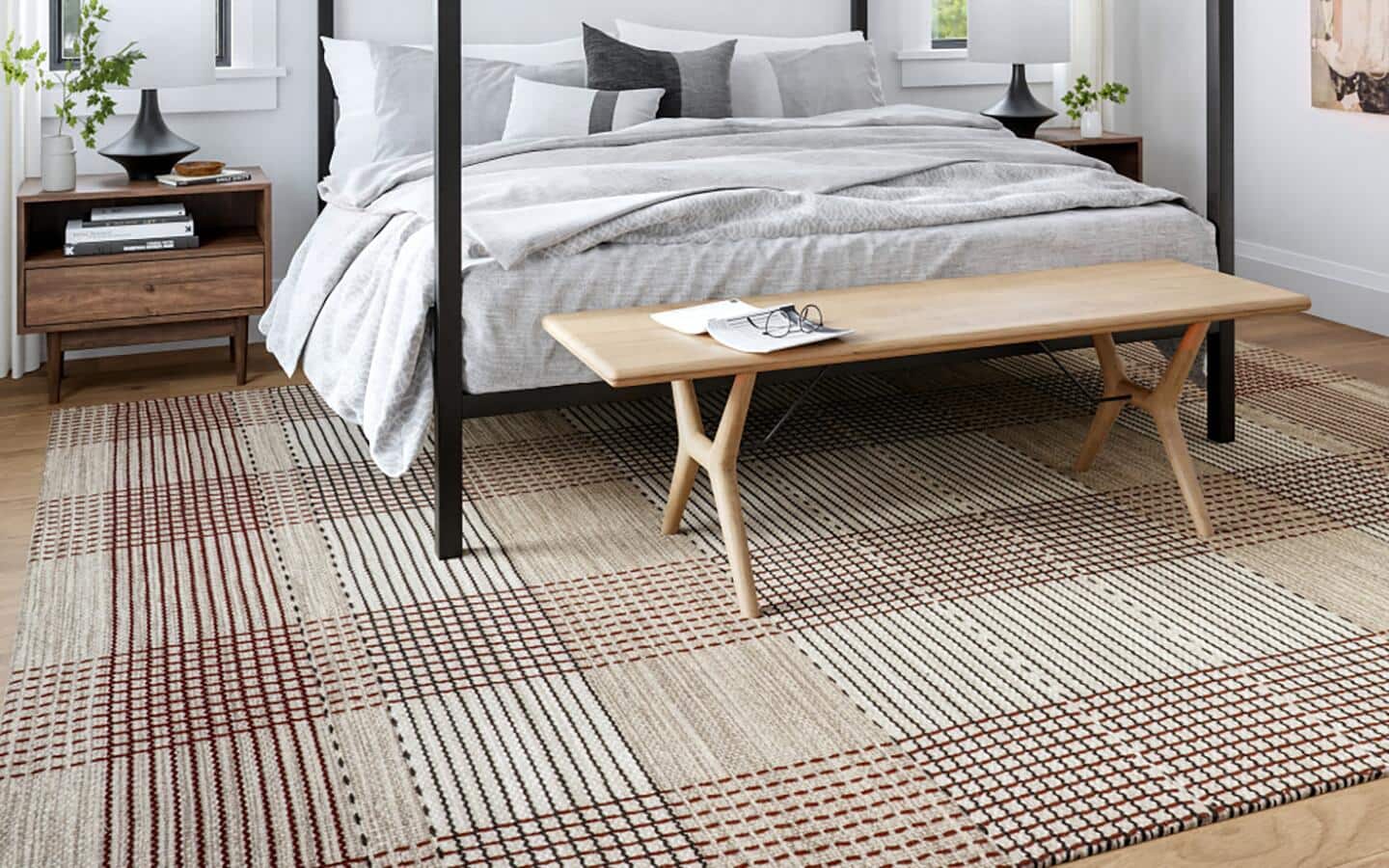 A brown and white plaid rug placed under a poster bed.