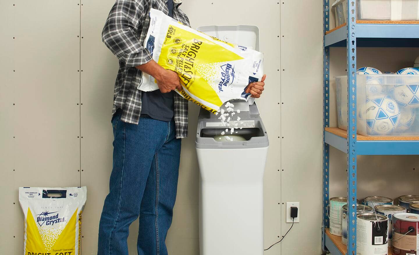 A person adds water softener salt to a water softener tank.