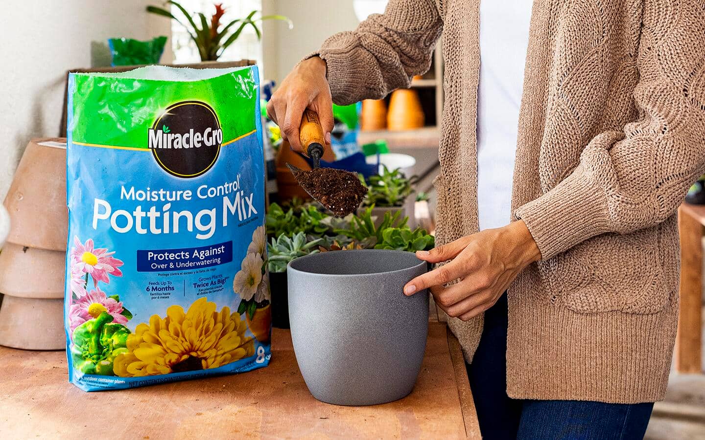 A person fills a round planter with potting soil.