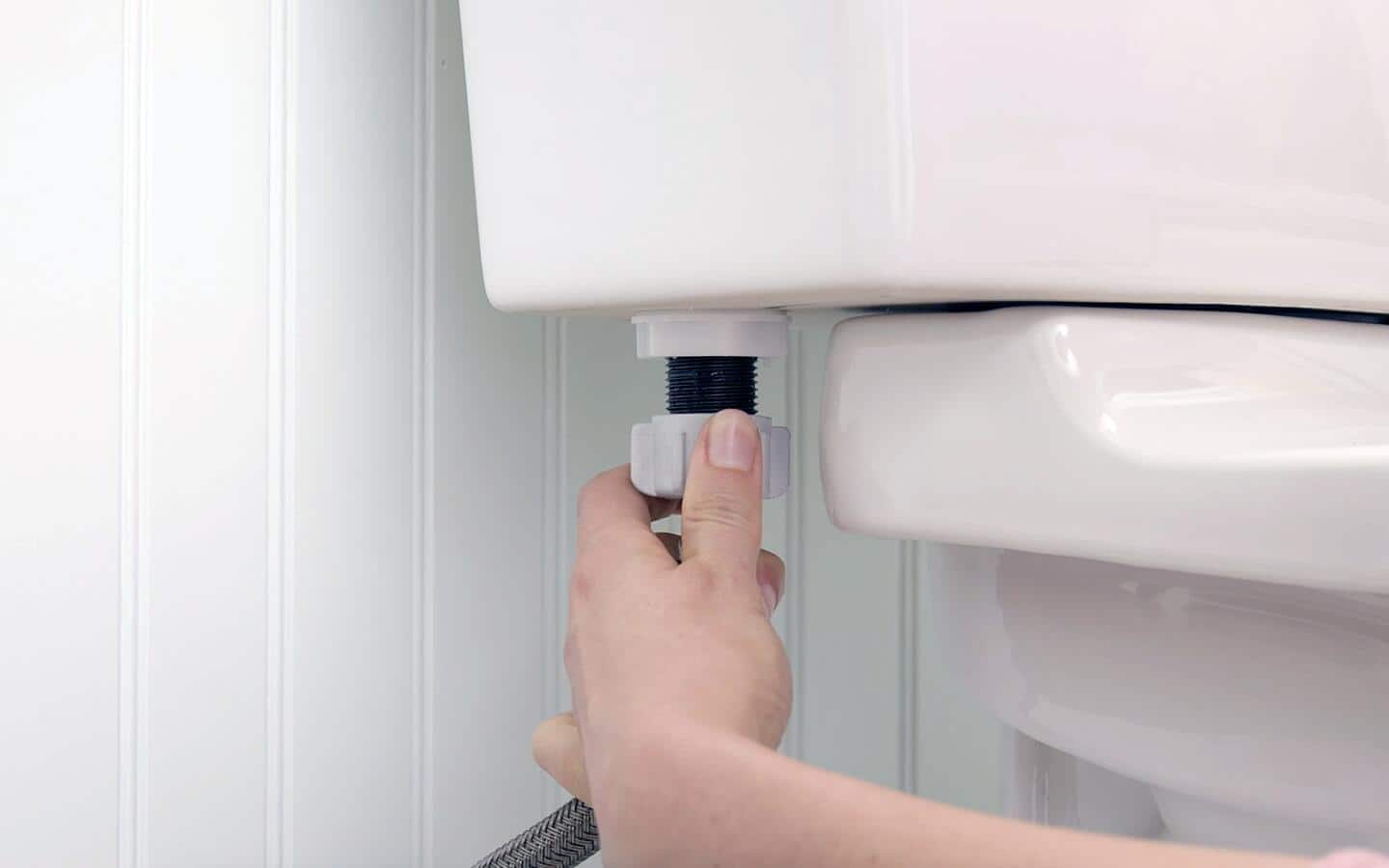 A person adjusting the refill tube on a toilet. A person adjusting the refill tube on a toilet.