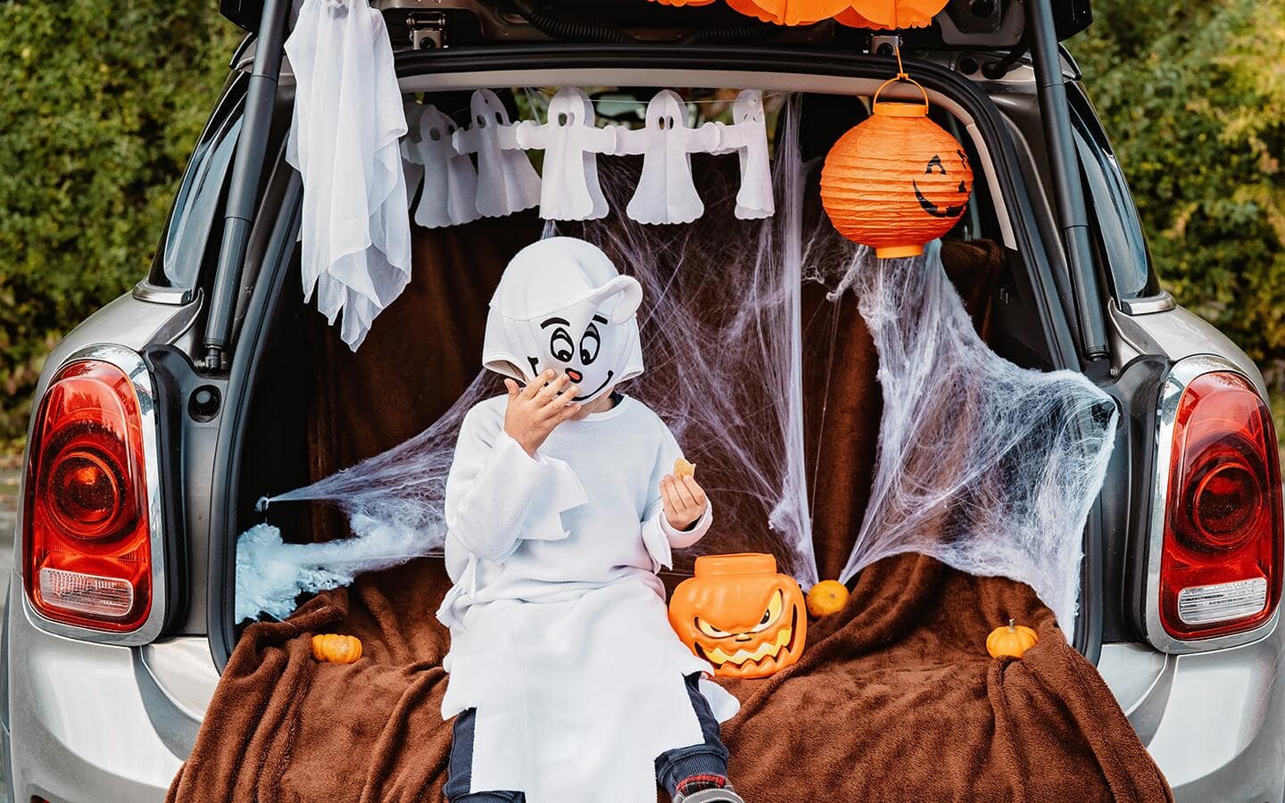 A person sits in a car trunk that's decorated for trunk or treat. A person sits in a car trunk that's decorated for trunk or treat.