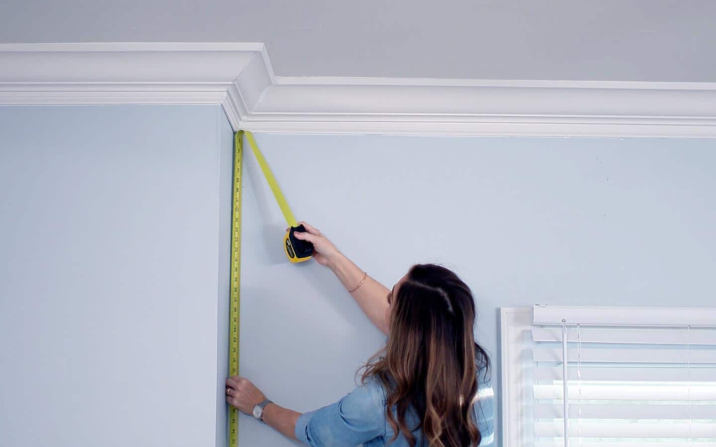A person measuring a wall for a built-in bookshelf. A person measuring a wall for a built-in bookshelf.