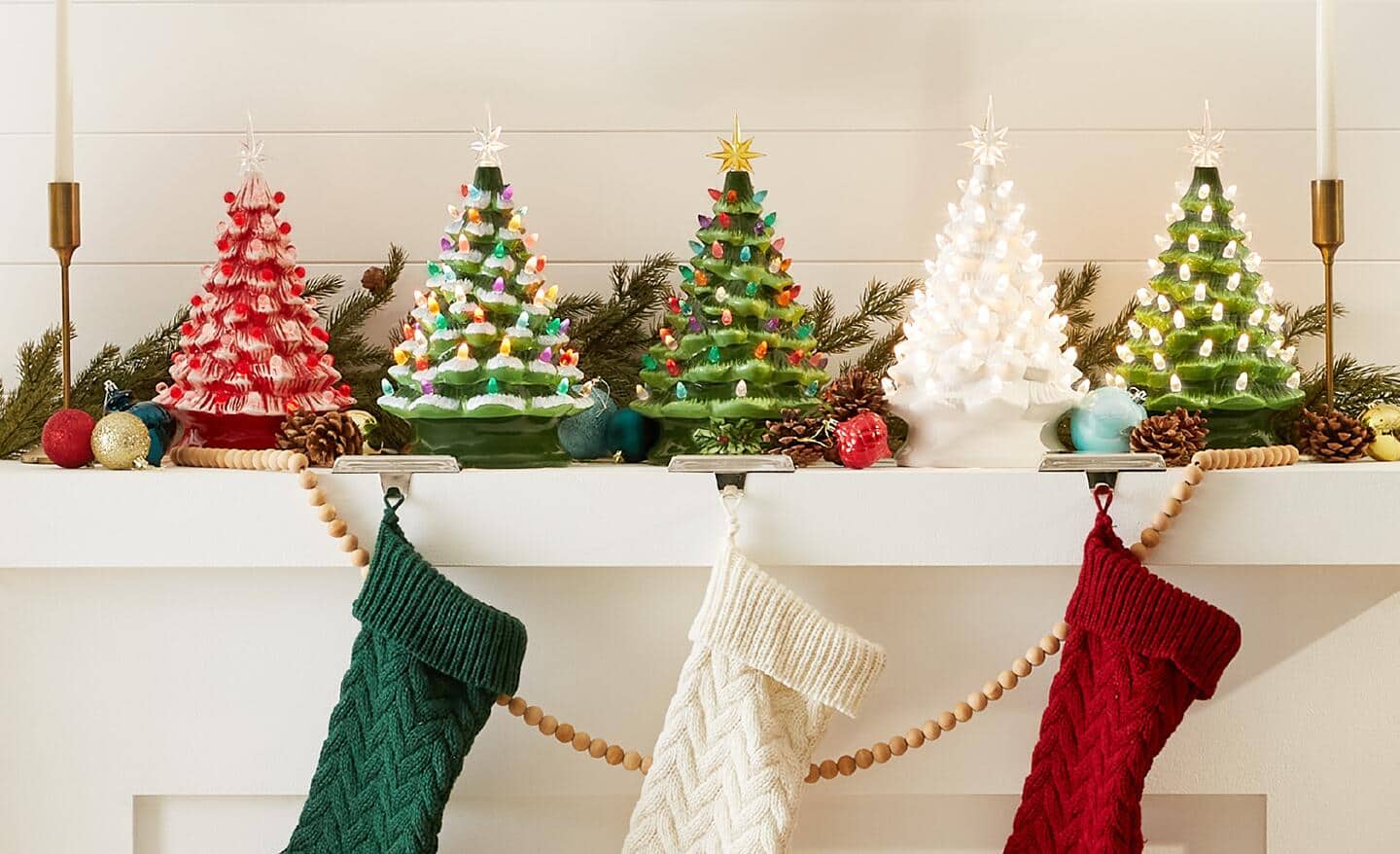 Lit ceramic Christmas trees sit on a mantel. Lit ceramic Christmas trees sit on a mantel.