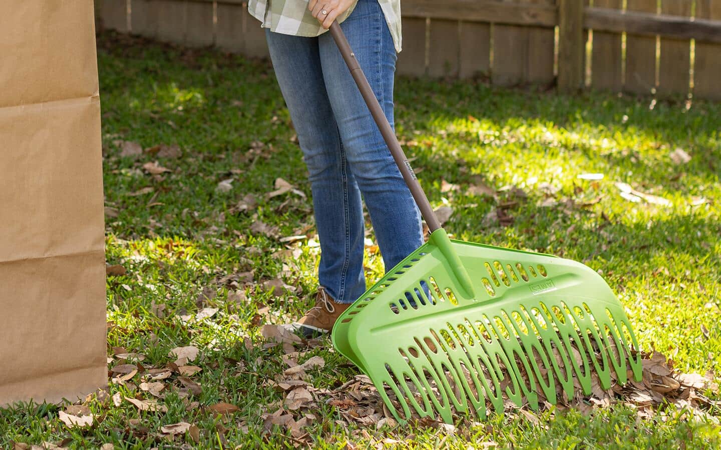  A person cleans up autumn leaves with a green rake.