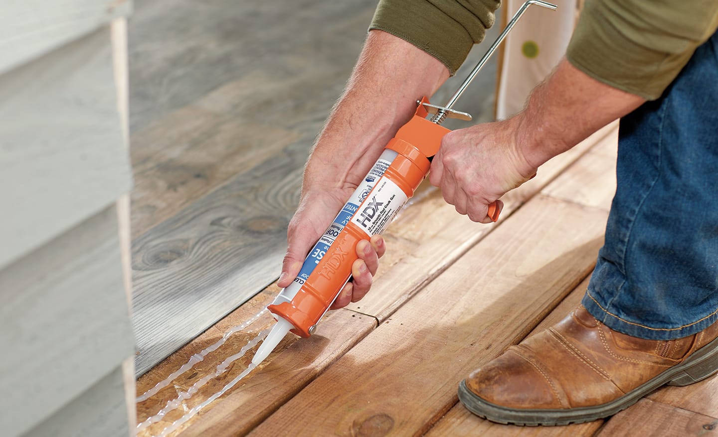 A man caulking the frame of a home entryway.