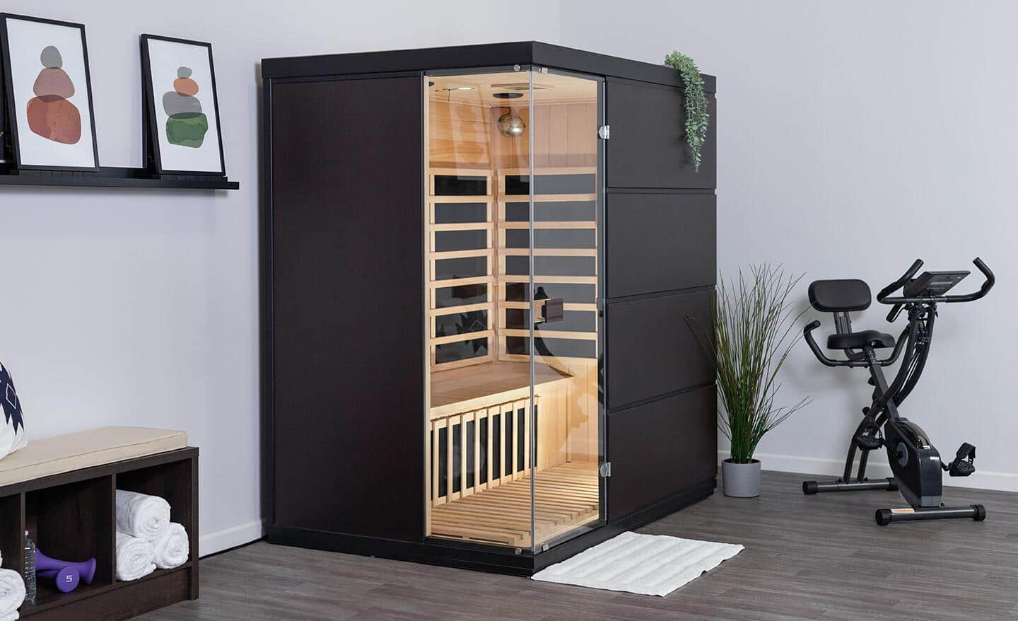 A dark wood sauna, with glass doors, sitting in an exercise room.