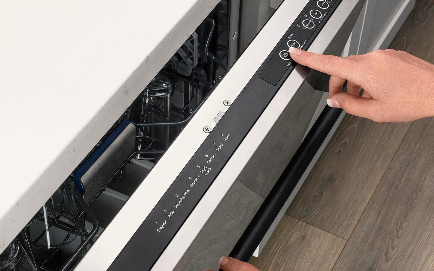 A hand reaching to press start on the top control panel of a dishwasher A hand reaching to press start on the top control panel of a dishwasher