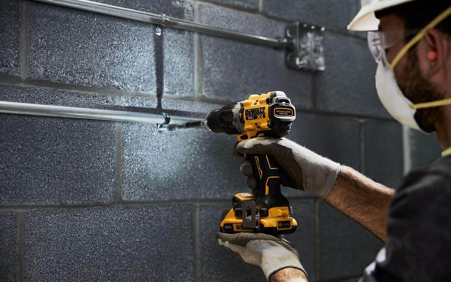 A person wearing safety equipment uses a cordless drill.