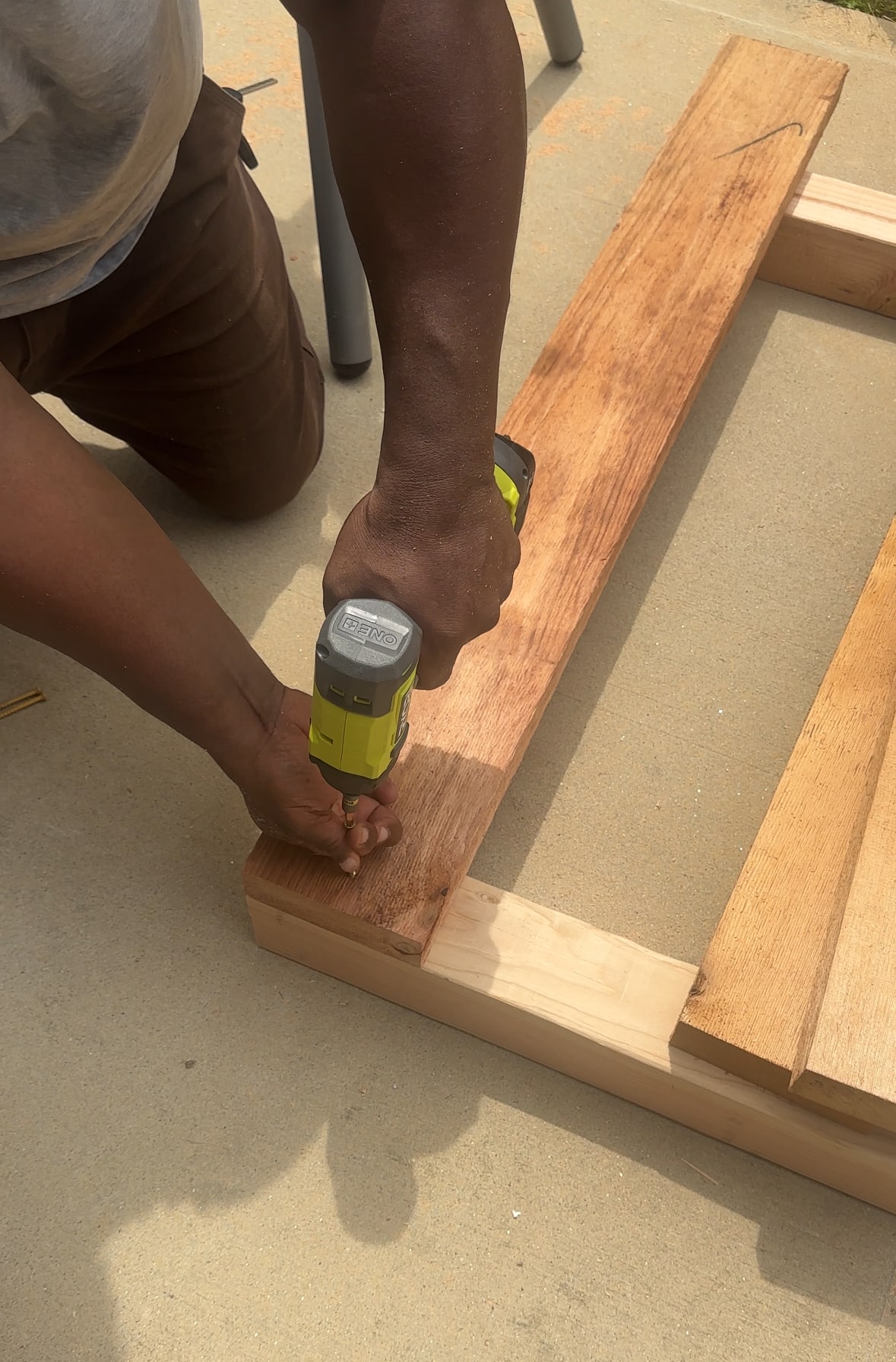 Someone using a RYOBI drill to connect two pieces of lumber with a screw. Someone using a RYOBI drill to connect two pieces of lumber with a screw.