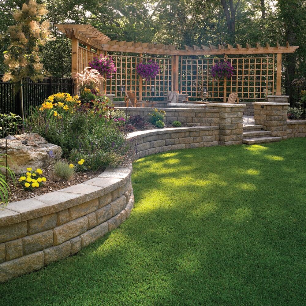 A curved retaining wall that frames garden beds and a patio in a backyard. 