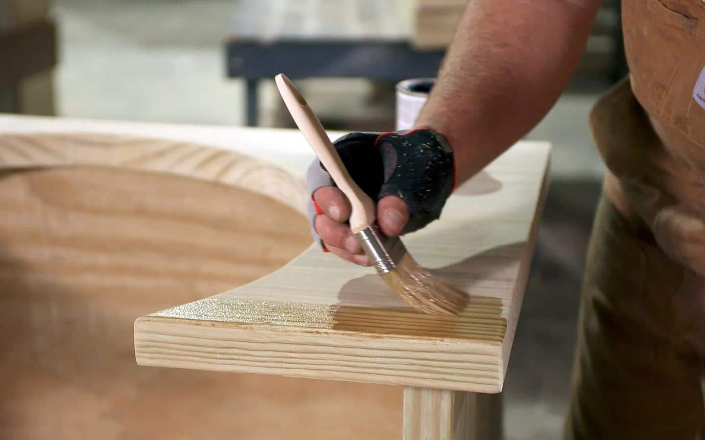 An individual stains the shelves of an outdoor Kamado grill station.