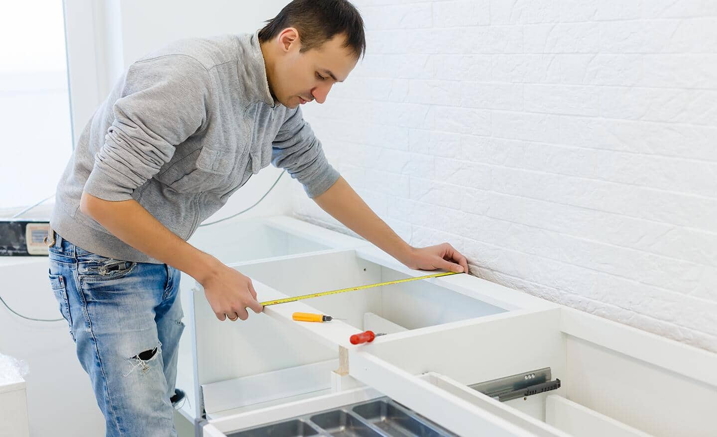 A person makes a measurement of the space to install the countertop.