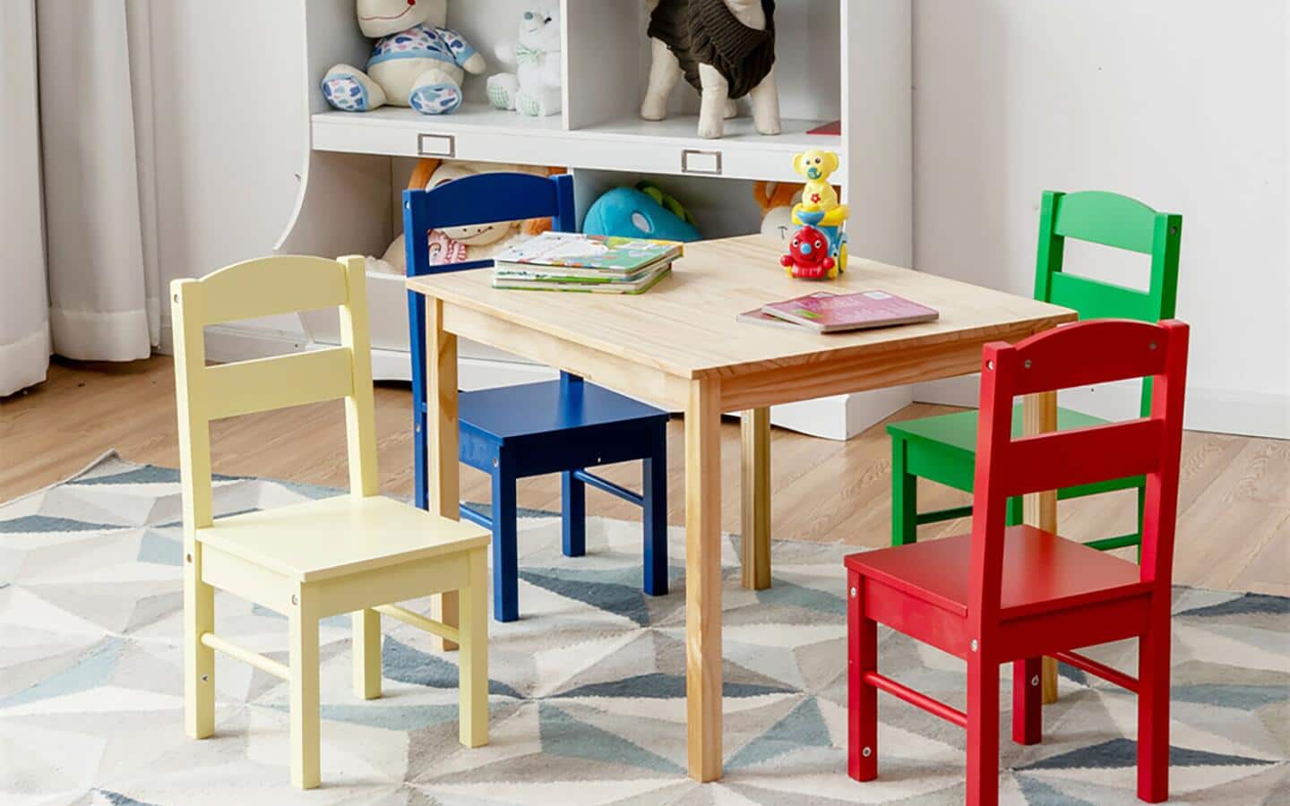A playroom with a small table and four differently colored chairs.