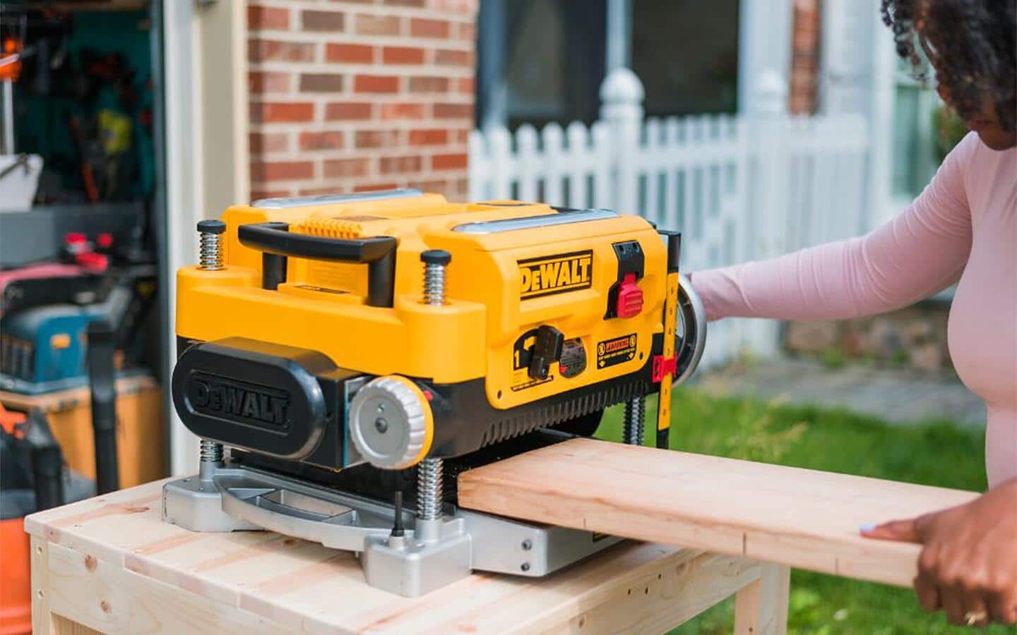 A woman uses a lathe outside a workshop. A woman uses a lathe outside a workshop.