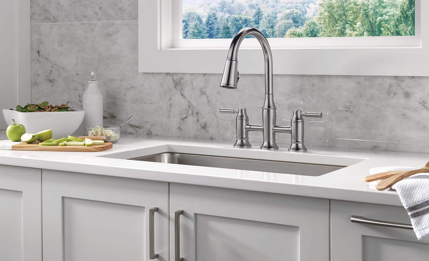 A marble backsplash behind a sink and white countertop. A marble backsplash behind a sink and white countertop.