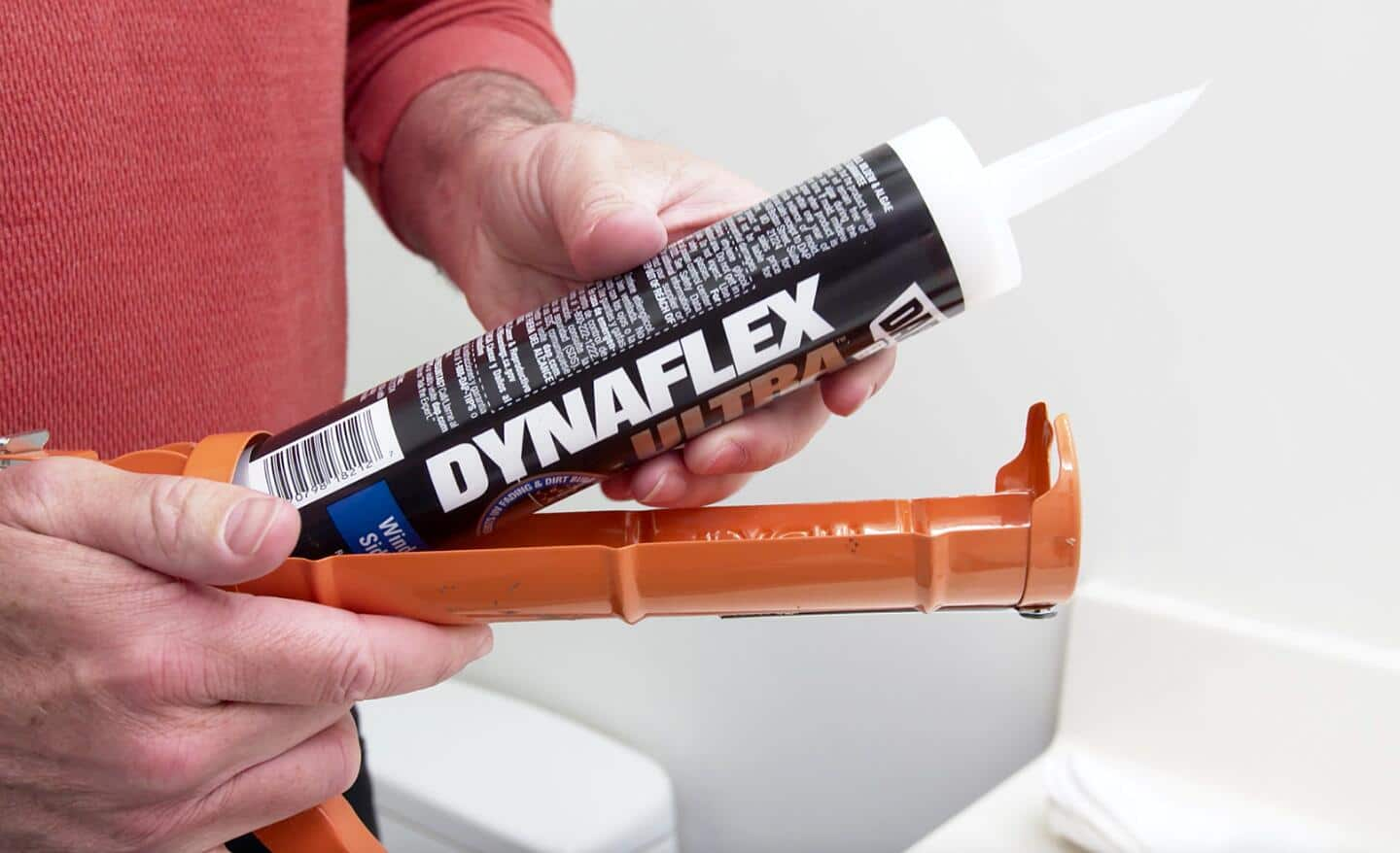 A person loads a tube of caulk into a caulk gun.