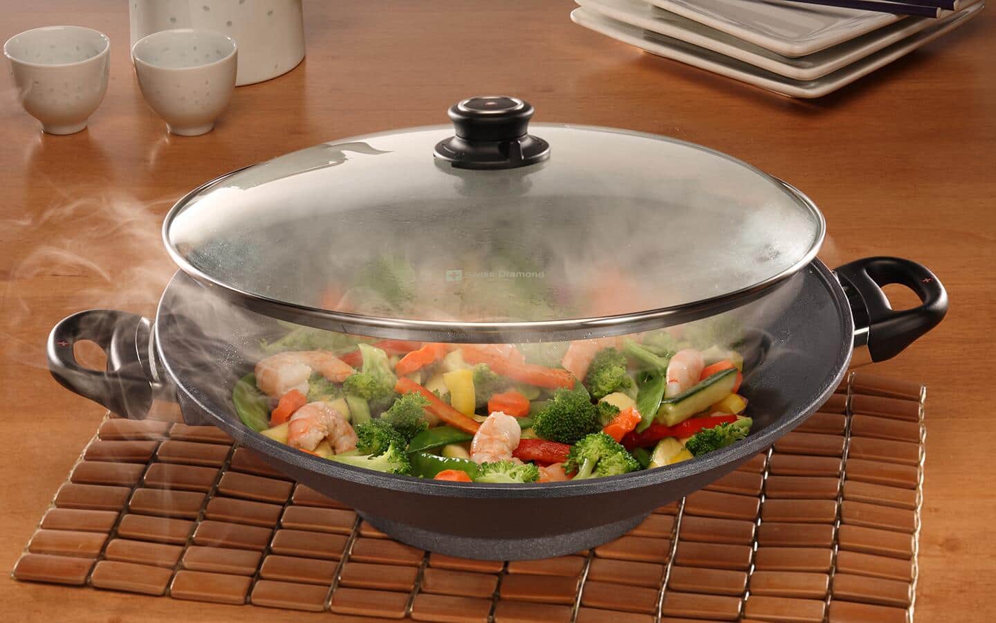 A wok on a table filled with steaming hot food. A wok on a table filled with steaming hot food.