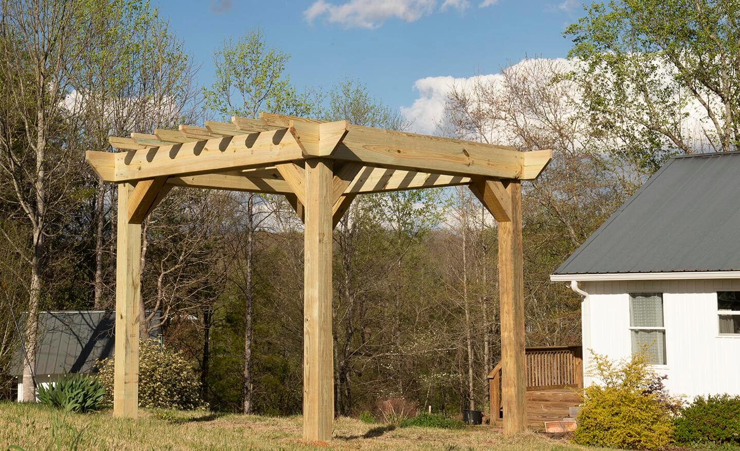 The finished pergola with a house and trees in the background.