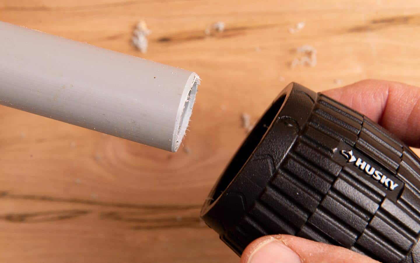 A person deburring the end of a piece of conduit.