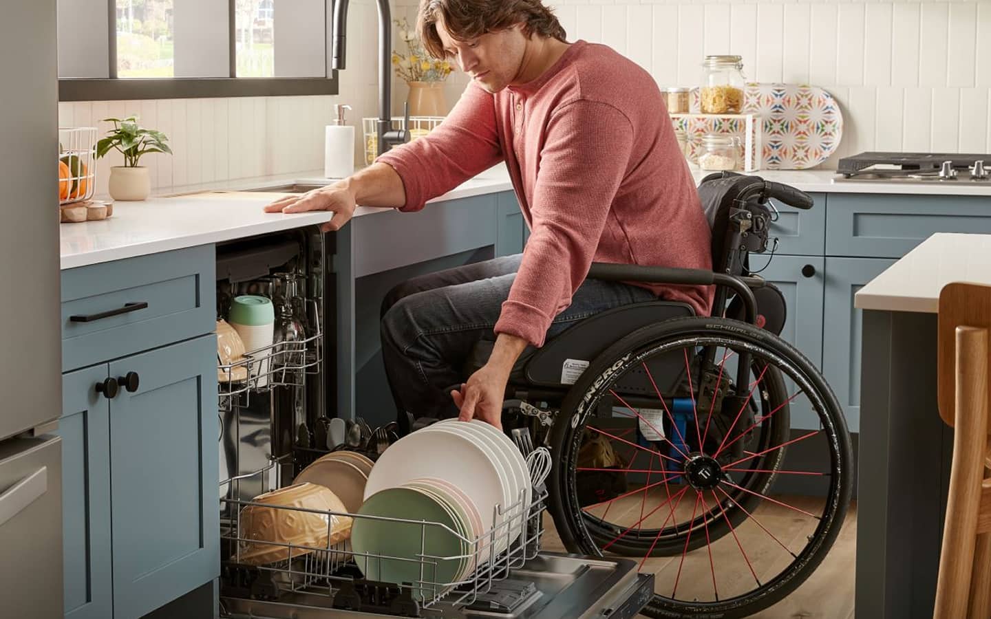 A person in a wheelchair loads an ADA-compliant dishwasher.