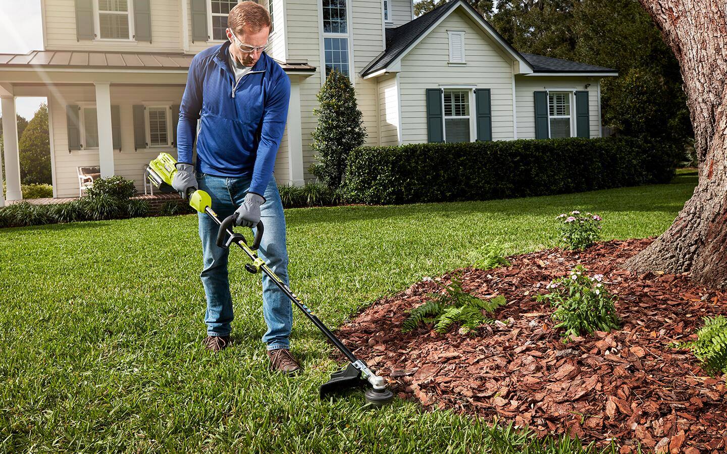 A man uses an edge trimmer to maintain the edge of his lawn.