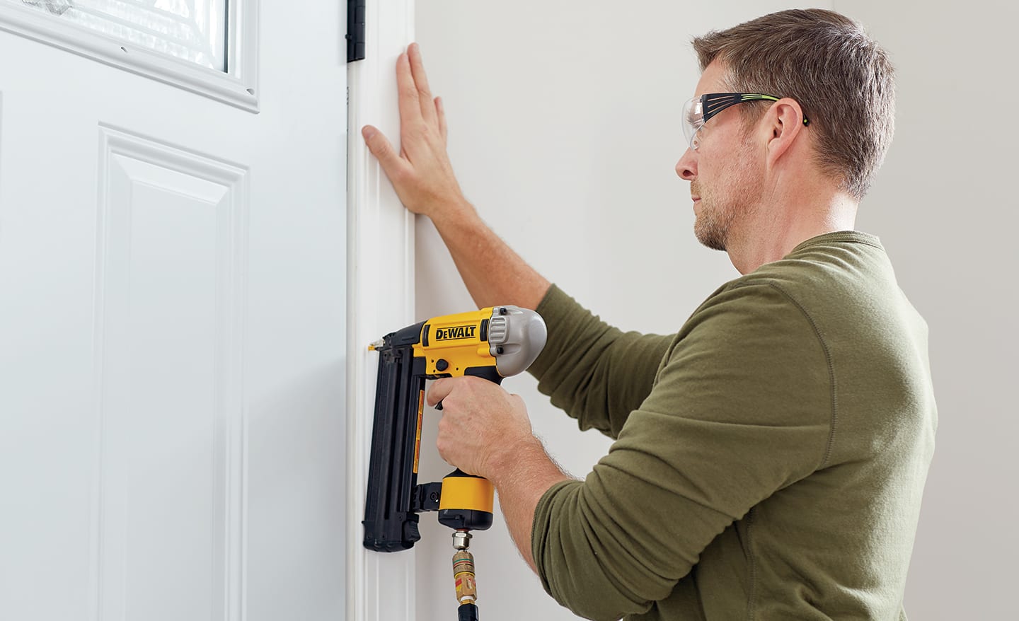 A man anchoring moulding inside the home.