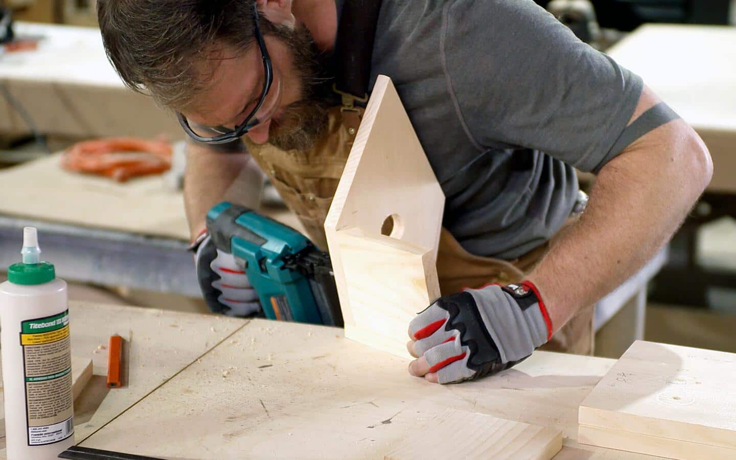 A person drills the front and a side panel of a birdhouse together.