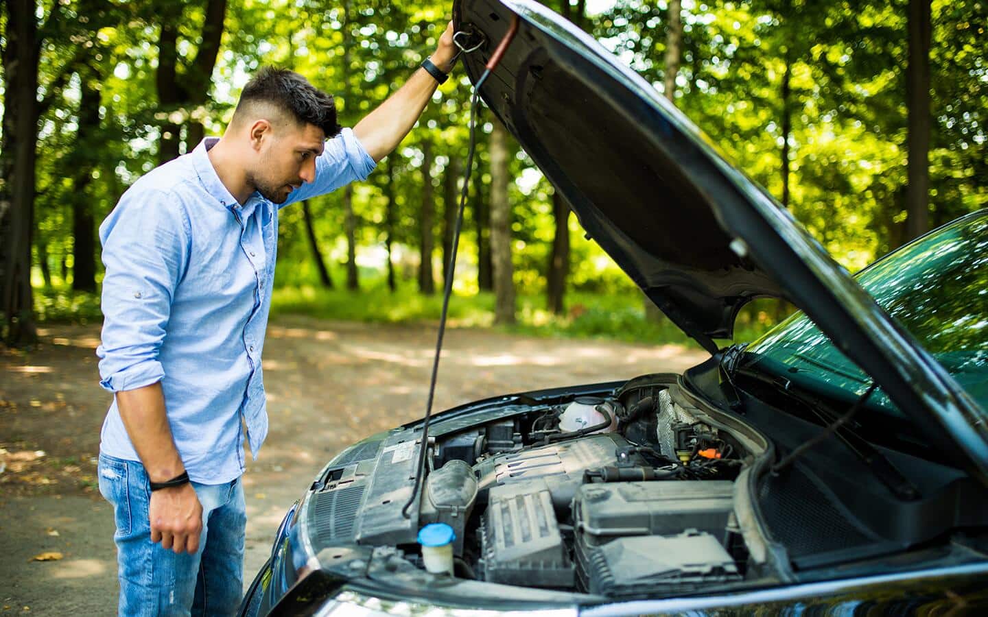 A man opens the hood of a car.