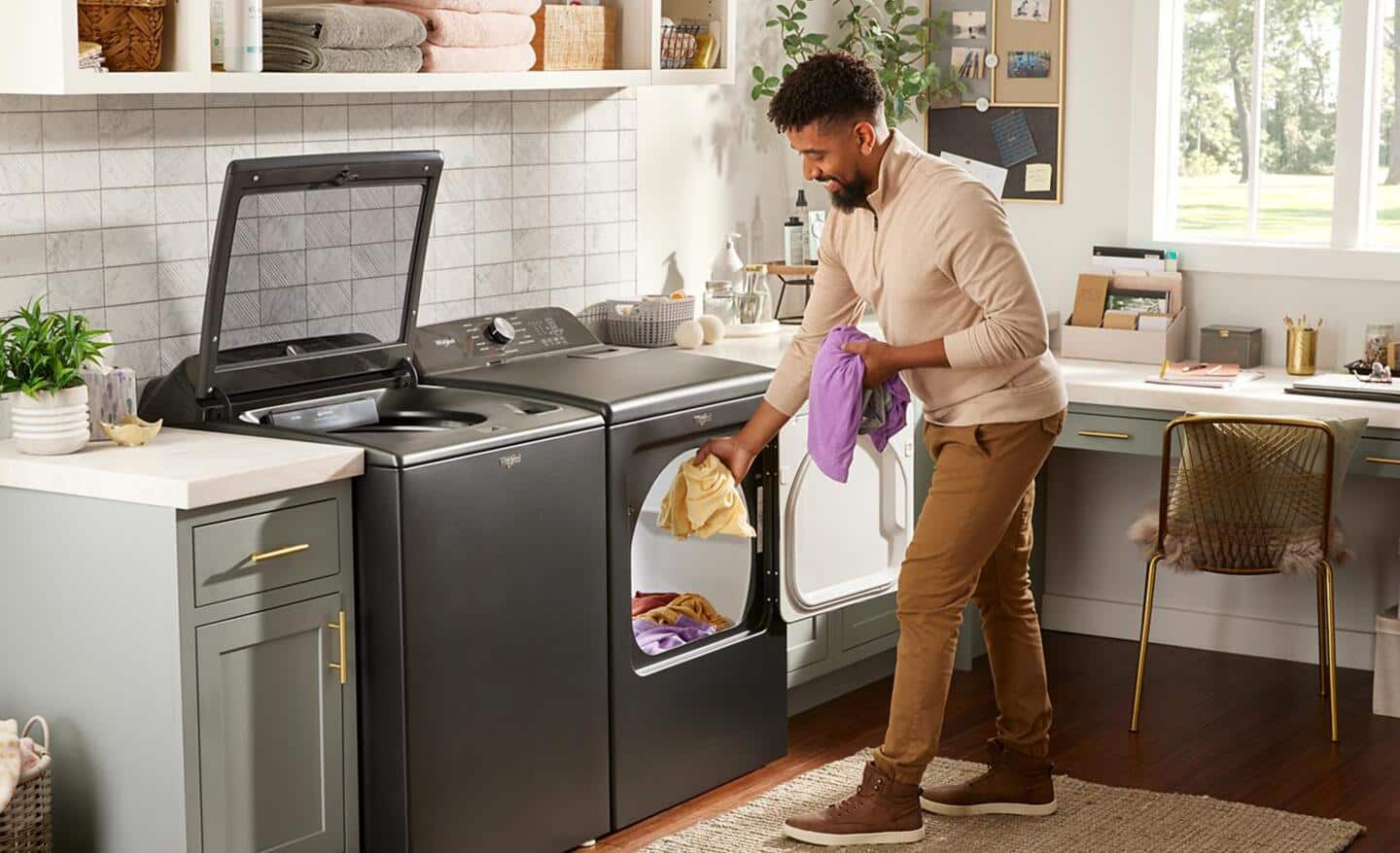 Someone standing in the kitchen and taking laundry out of his dryer.