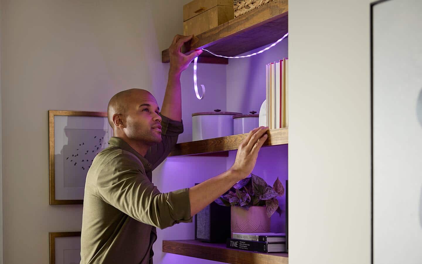 A person installs smart LED lights in a shelving unit.