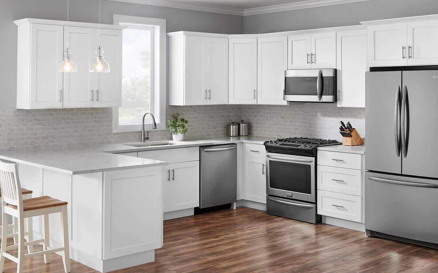 A white kitchen featuring stock cabinets with silver hardware. A white kitchen featuring stock cabinets with silver hardware.