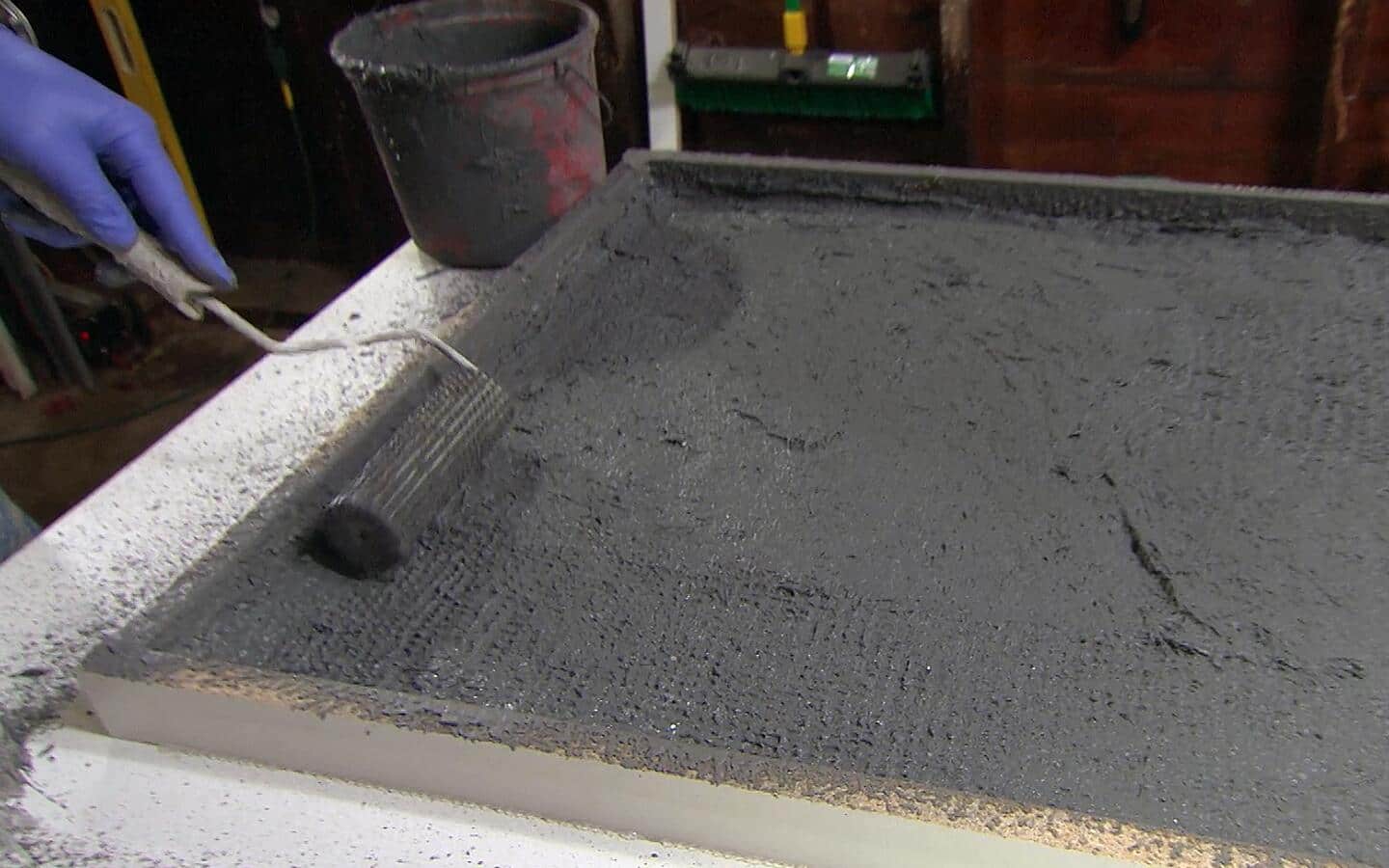 A person smooths concrete into a form to remove air bubbles. A person smooths concrete into a form to remove air bubbles.