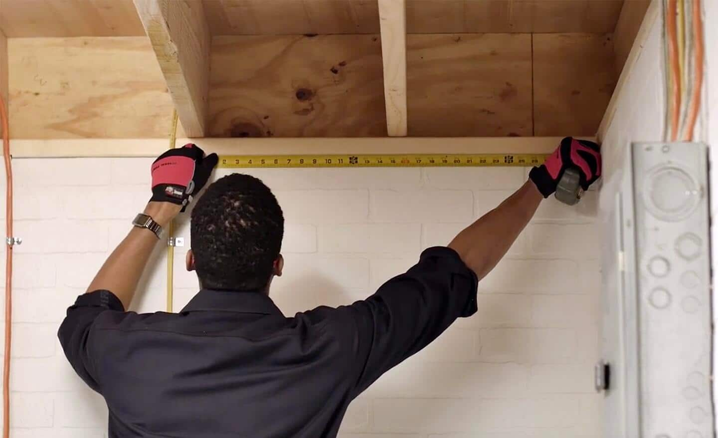 A person measuring a path through the basement for installing a dryer vent.