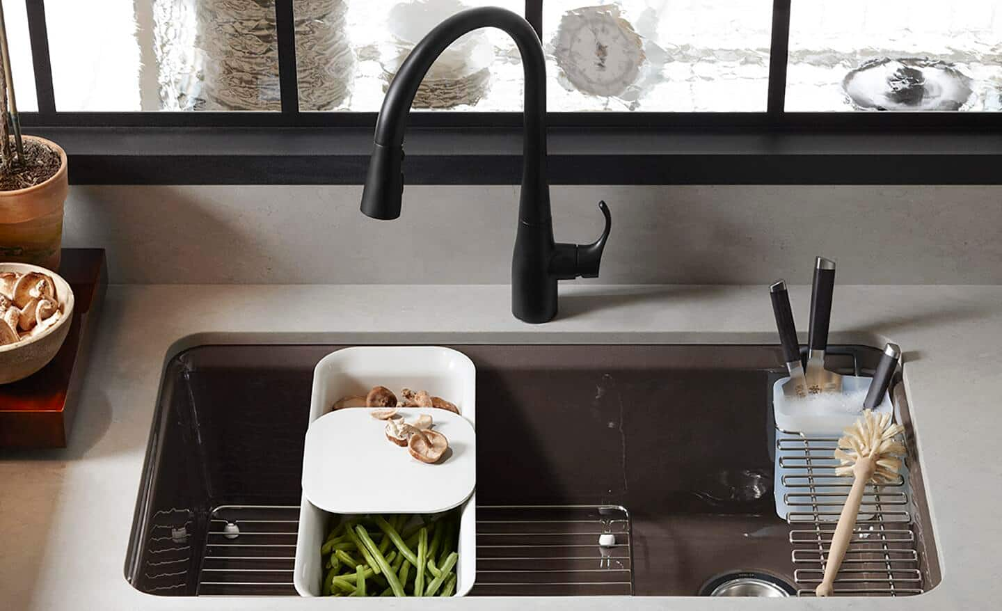 A brushed metal kitchen sink with a black faucet.