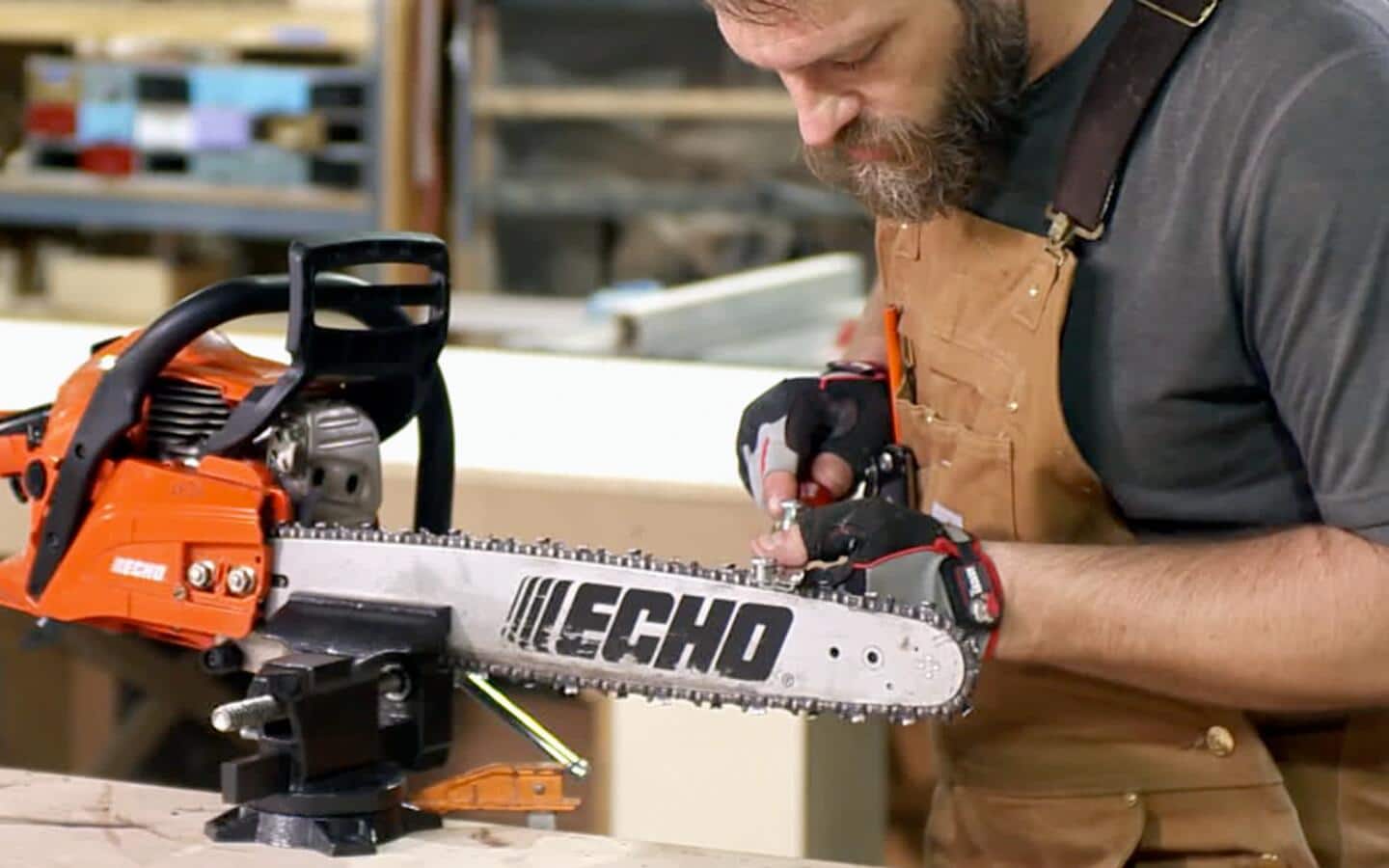 A person looks down as he uses a guide and a file while sharpening the chain of a chainsaw. A person looks down as he uses a guide and a file while sharpening the chain of a chainsaw.