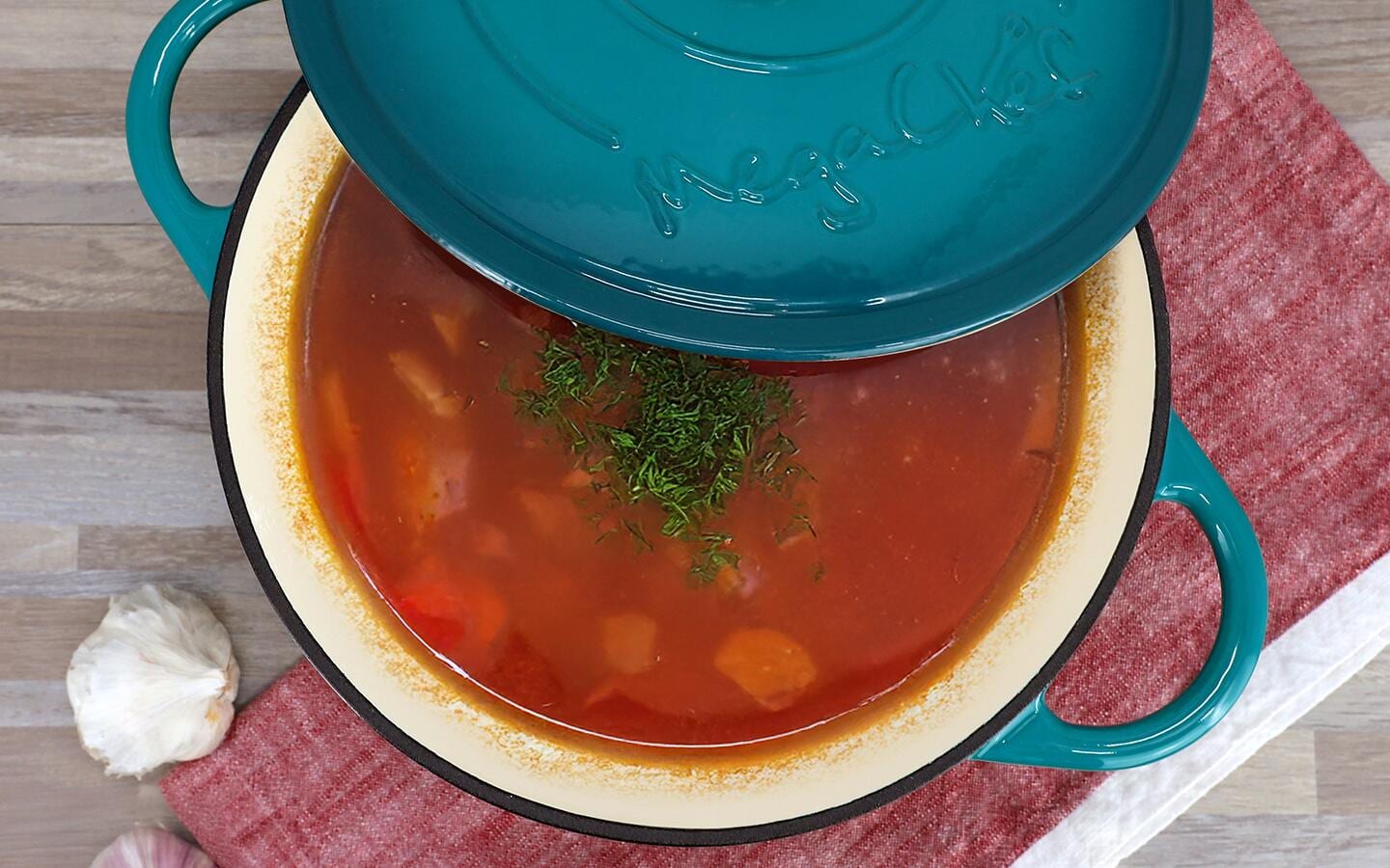 A porcelain enamel stock pot filled with a tomato stew.