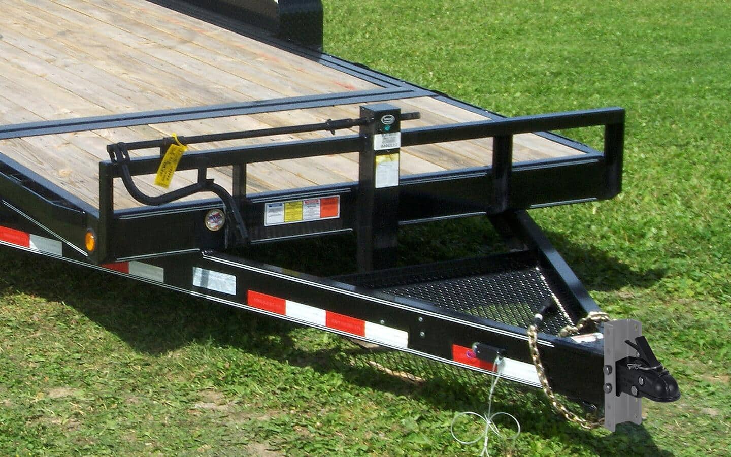 A black, red and white trailer hitch attached to a flatbed trailer.