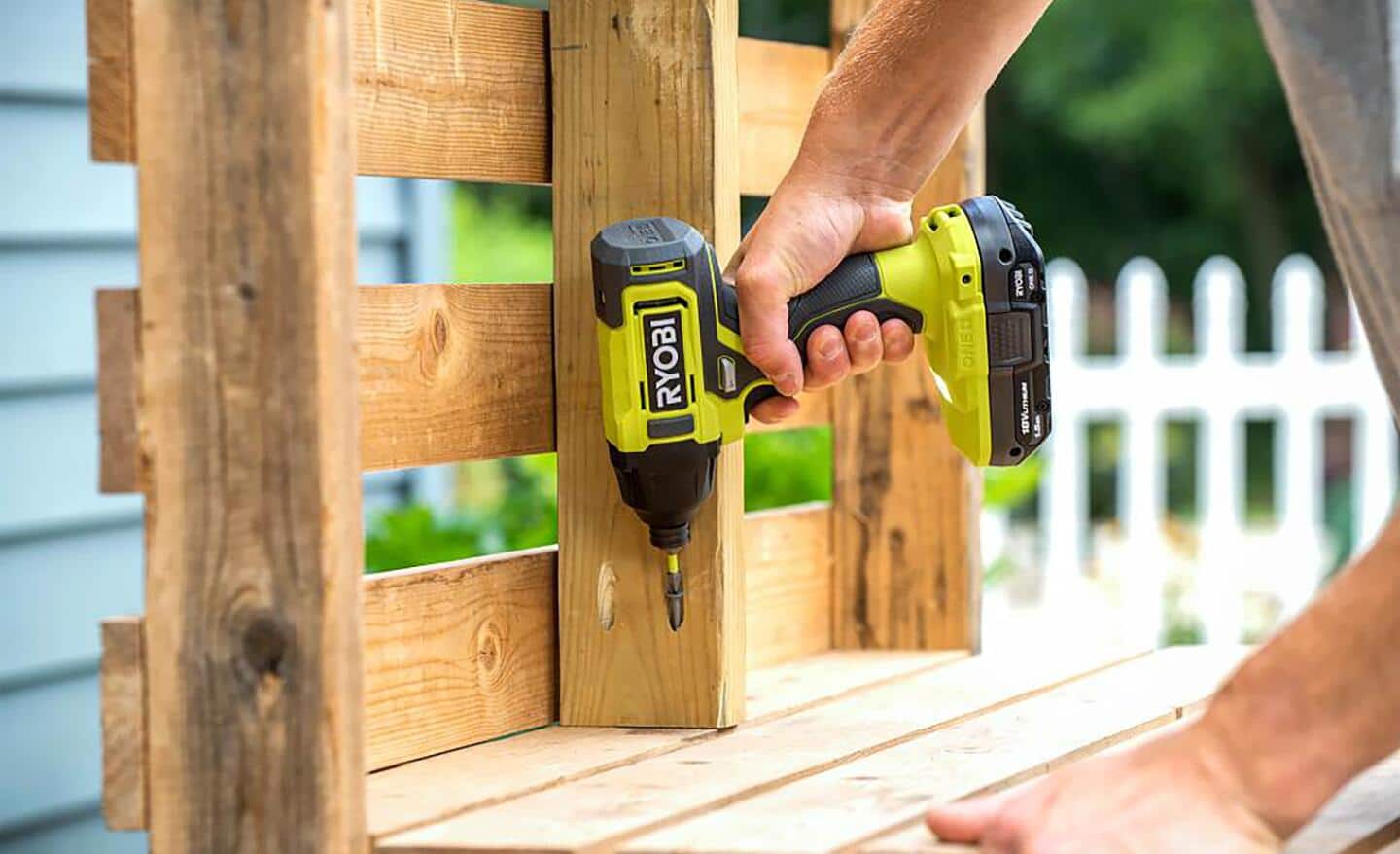 A person using an impact driver on a plywood crate.