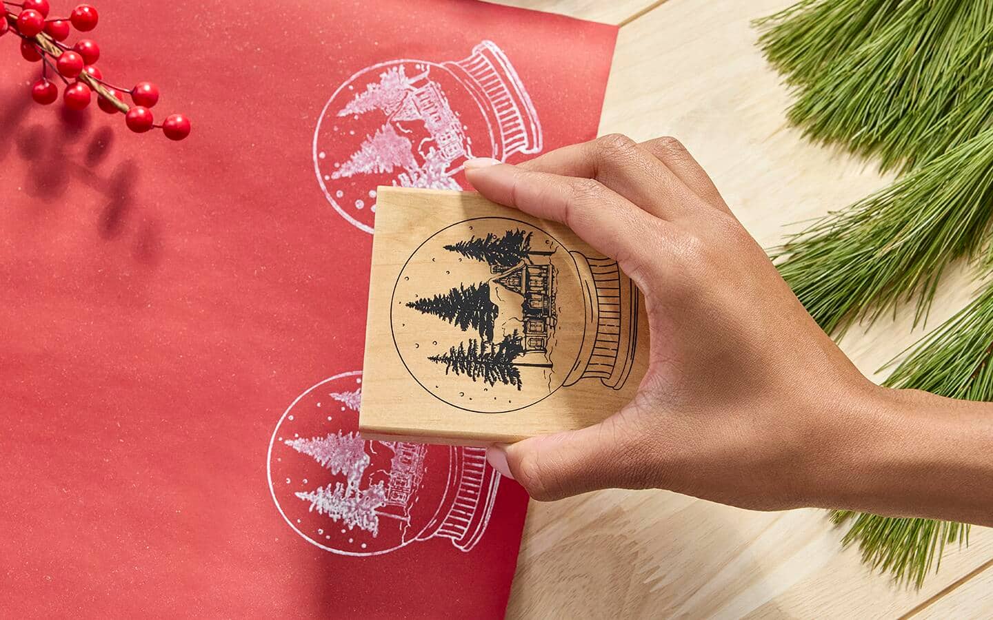 Person holding stamp block over red paper with stamp imprint in white ink