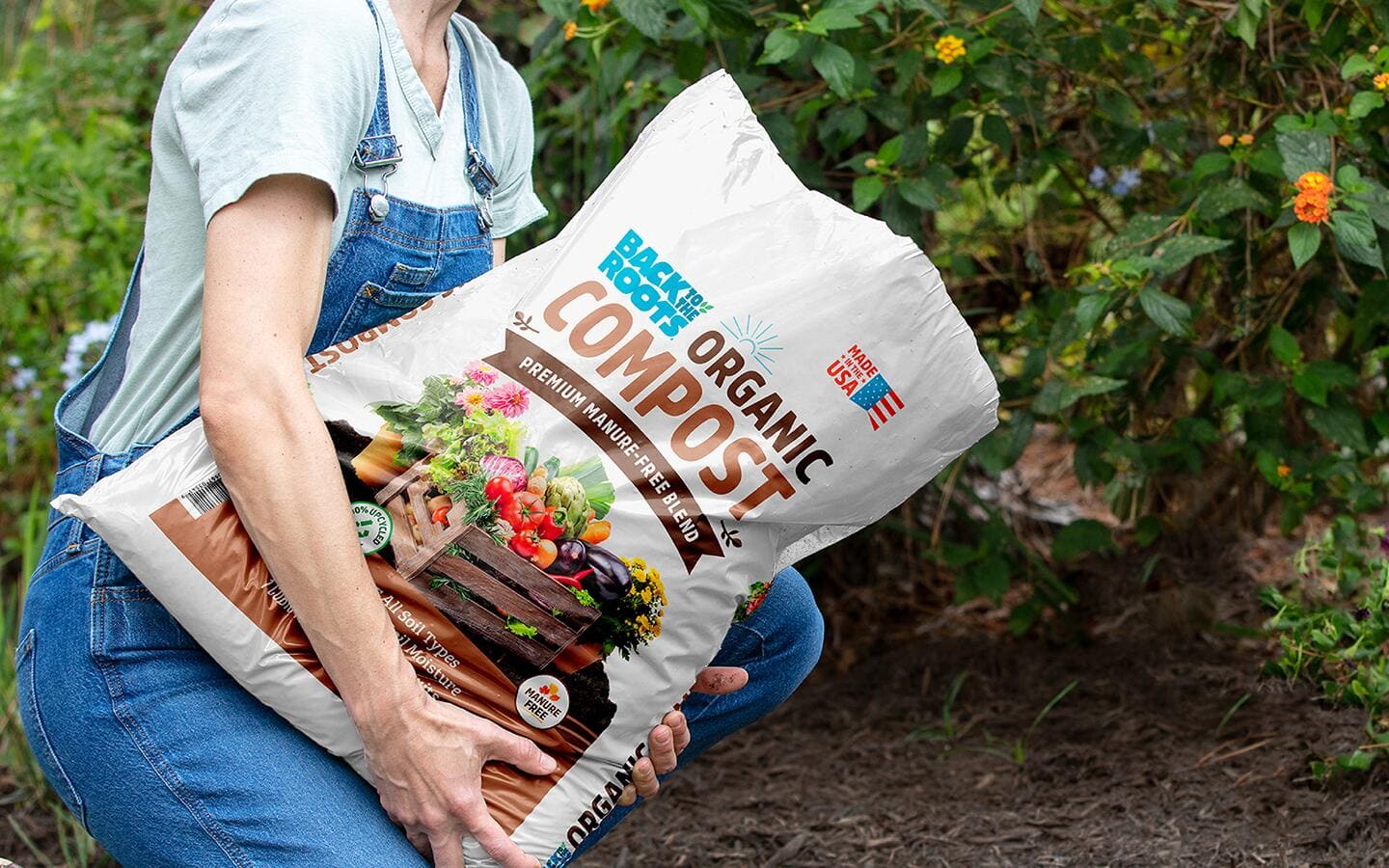 Gardener holds bag of organic compost in a vegetable garden Gardener holds bag of organic compost in a vegetable garden