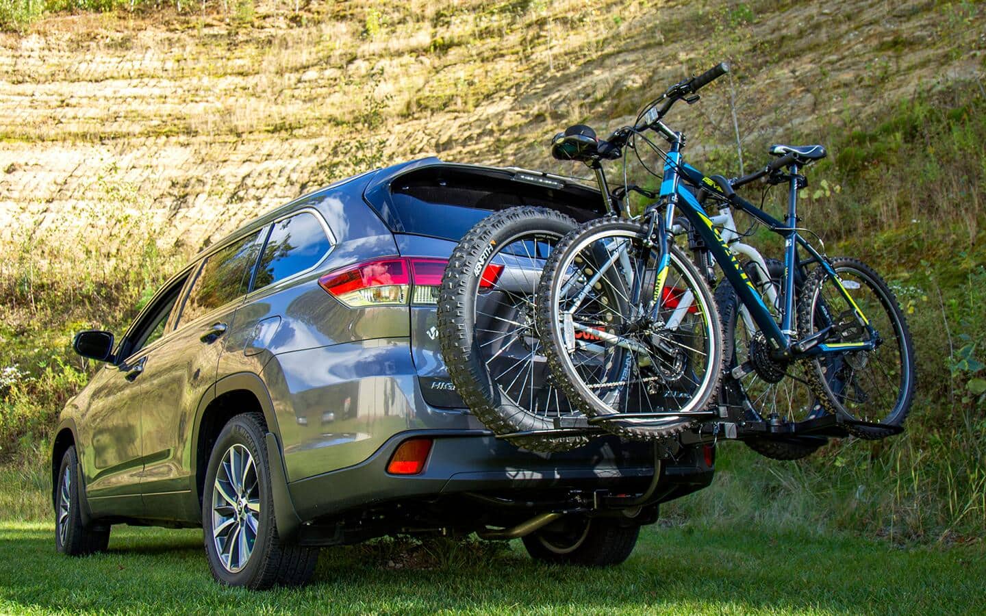 A grey SUV with a trunk-mounted bike rack holding a pair of bicycles.