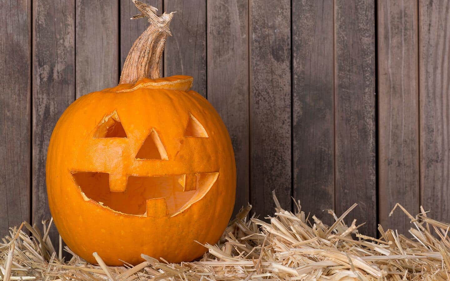 A carved pumpkin arranged on hay.