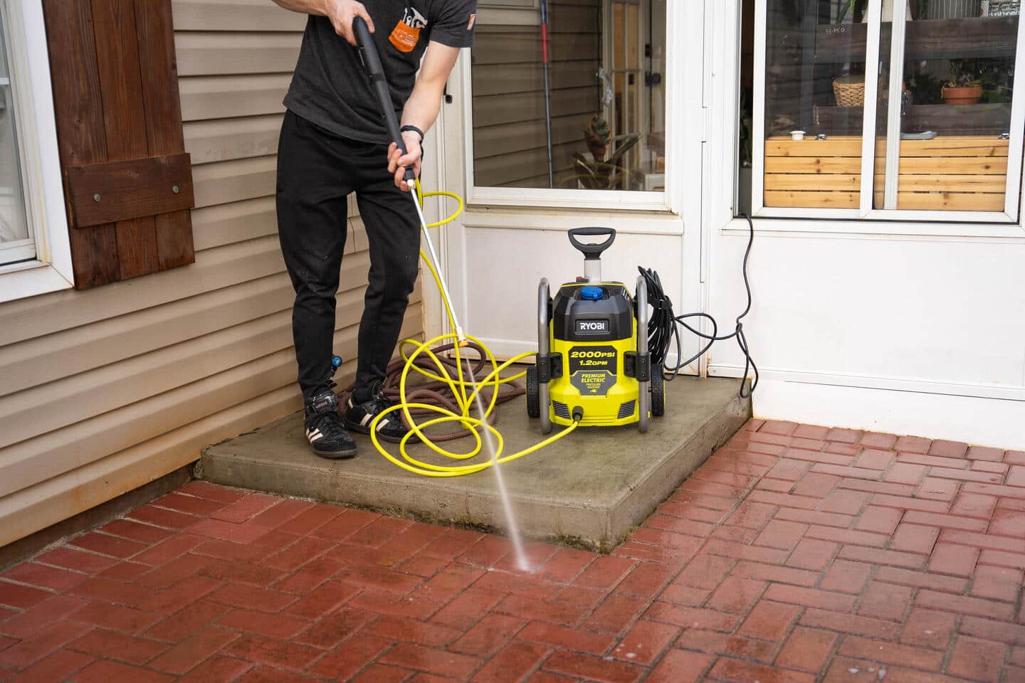Tyson uses the powerful pressure washer to blast away dirt and mildew from the brick pavers on his back patio. 