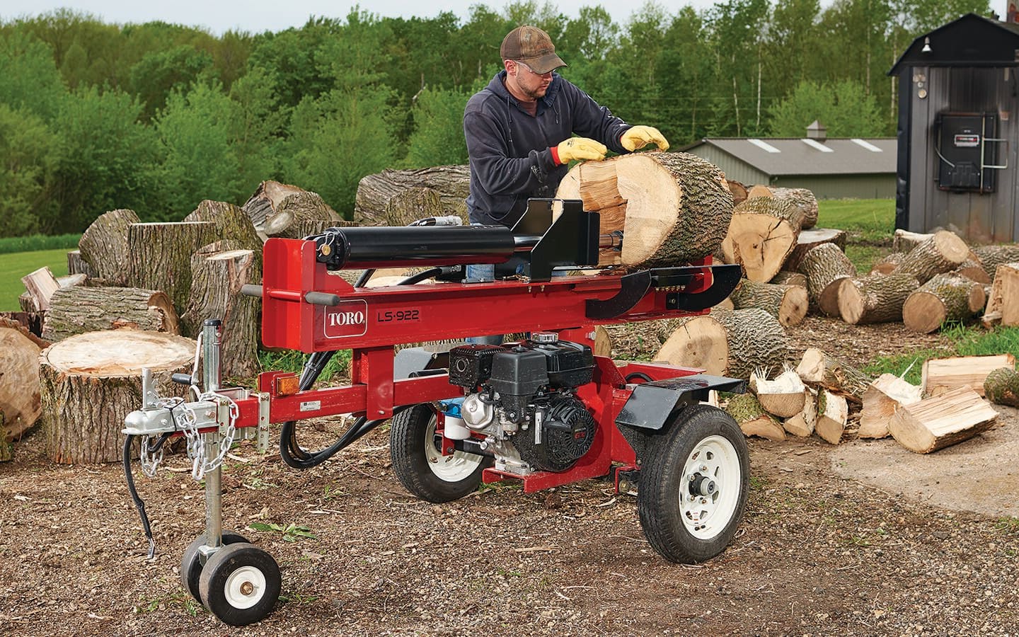 A person uses a log splitter to split a large log.
